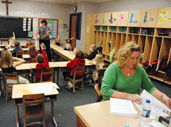 Leah McCool, right, serves as a volunteer teacher’s aide in the first-grade classroom at St. Michael School in Brookville. In the background, St. Michael School first-grade teacher Melanie Back asks her students a question on Jan. 7. (Photo by Sean Gallagher) 