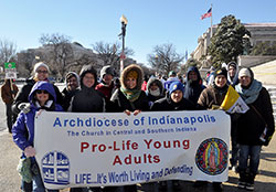 Andrew Costello, second from left, leads a prayer on the night of Feb. 21 as members of Operation Leftover take to the streets of downtown Indianapolis to provide food, clothing and conversation with people who are homeless. The group of young adult Catholics dedicated to helping the homeless is based at St. John the Evangelist Parish in Indianapolis. Costello prays with a man who is homeless, left, and two other members of the group, Michael Gramke, second from right, and Kellye Cramsey. (Photo by John Shaughnessy)