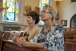 Marcia Adams, left, and Deb Dalley kneel in prayer on June 24 in St. Vincent de Paul Church in Shelby County. Earlier this year, Dalley donated a kidney to Adams. Both are members of the Batesville Deanery faith community. (Photo by Sean Gallagher)