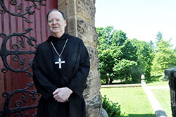 Benedictine Archabbot Kurt Stasiak stands next to the Archabbey Church of Our Lady of Einsiedeln in St. Meinrad on June 6. The monks of Saint Meinrad Archabbey elected Archabbot Kurt to be their 10th abbot and seventh archabbot in the monastery’s 162-year history on June 2. (Photo by Sean Gallagher)