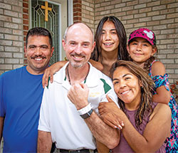 Father Christopher Wadelton poses for a photo with the family of Rebeca Barcenas, the woman he donated a kidney to on May 14. The family members are Rebeca’s husband, Rafael Ventura, left, and their two daughters, Jennifer and Carmen. (Photo by D. Todd Moore)