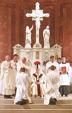 Archdiocesan priests ritually lay hands on transitional Deacons José Neri, left, and Jack Wright while Archbishop Charles C. Thompson, center, looks on during a June 3 priesthood ordination Mass at SS. Peter and Paul Cathedral in Indianapolis. (Photo by Sean Gallagher)