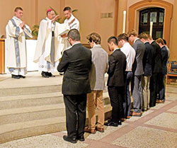 Archbishop Charles C. Thompson blesses nine new archdiocesan seminarians during an Aug. 15 Mass at SS. Peter and Paul Cathedral in Indianapolis. He is assisted by transitional Deacon Samuel Rosko, left, and altar server Joe Gehret. (Photo by Sean Gallagher)