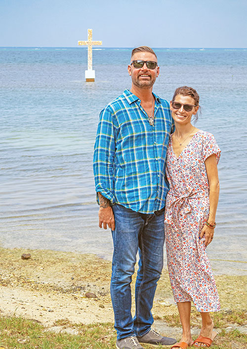 As a brightly-colored cross stands out in the Caribbean Sea, Matt and Nikki Javit, former members of Immaculate Heart of Mary Parish in Indianapolis, pose for a photo on the beach of Punta Gorda, Honduras. The Javits shared the cross with members of the faith community of St. Ignatius Parish in Punta Gorda, in appreciation for the way they have embraced the couple during the past two years of living there. (Submitted photo)