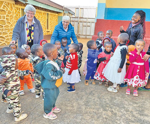 During a recent visit in September, Benedictine Sister Mary Luke Jones (second from left) and Community of International Benedictines moderator Benedictine Sister Lynn McKenzie (far left) share joy and playfulness with orphan children in Tanzania. (Submitted photo)