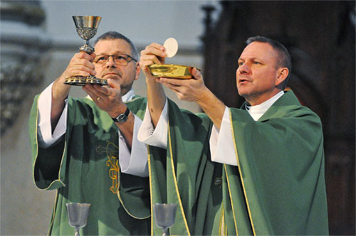 Deacon David Bartolowits, left, and Father Rick Nagel elevate the Eucharist during a Feb. 7, 2019, Mass at St. John the Evangelist Church in Indianapolis. (CNS photo/Sean Gallagher, The Criterion)